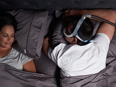 La pareja duerme en una casa. Uno de los miembros de la pareja utiliza la mascarilla nasal ResMed AirFit N30i