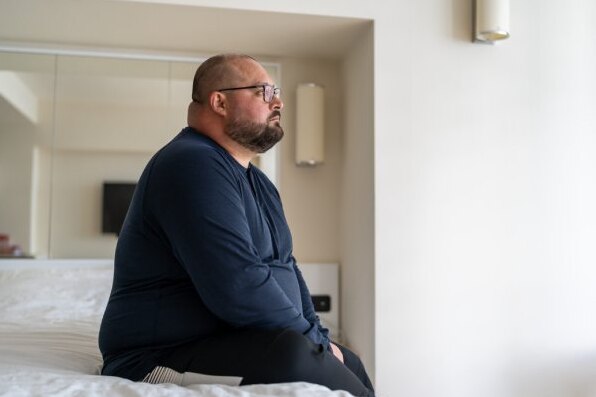  hombre inquieto sentado en el borde de la cama
