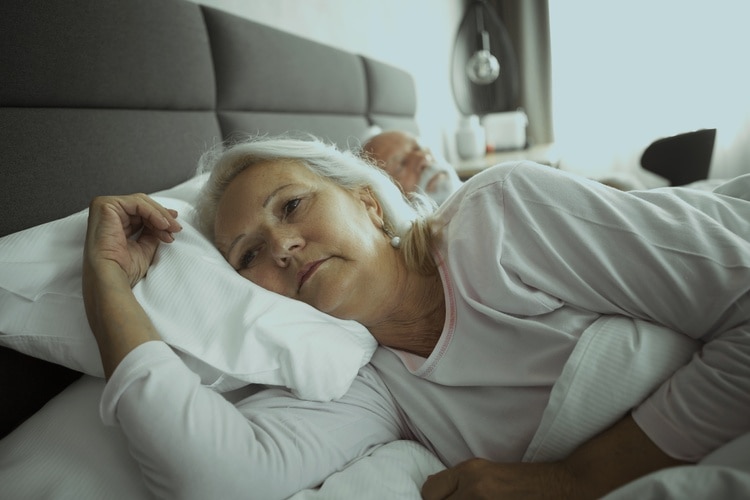 Mujer acostada en la cama sin poder dormir